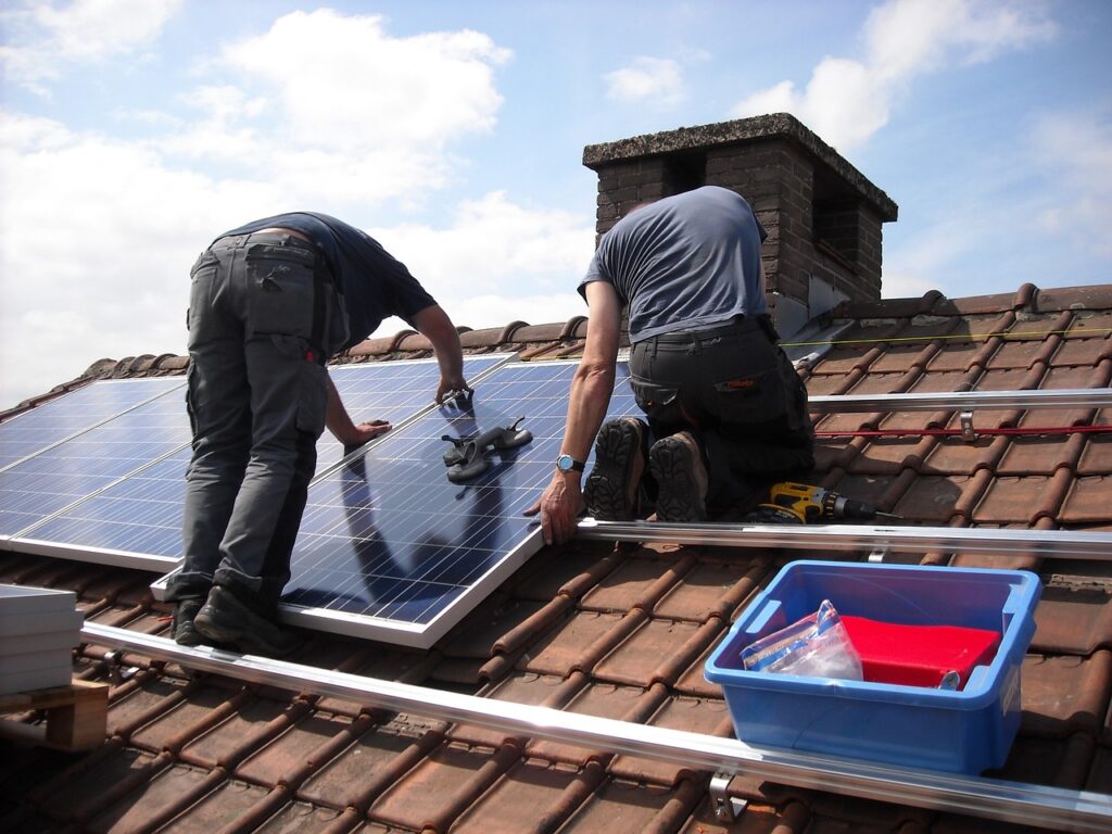 two solar installers on a roof with panels