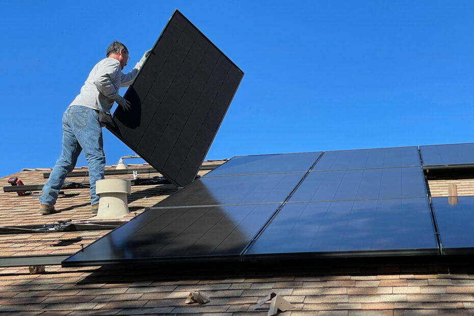 man on roof holding solar panel